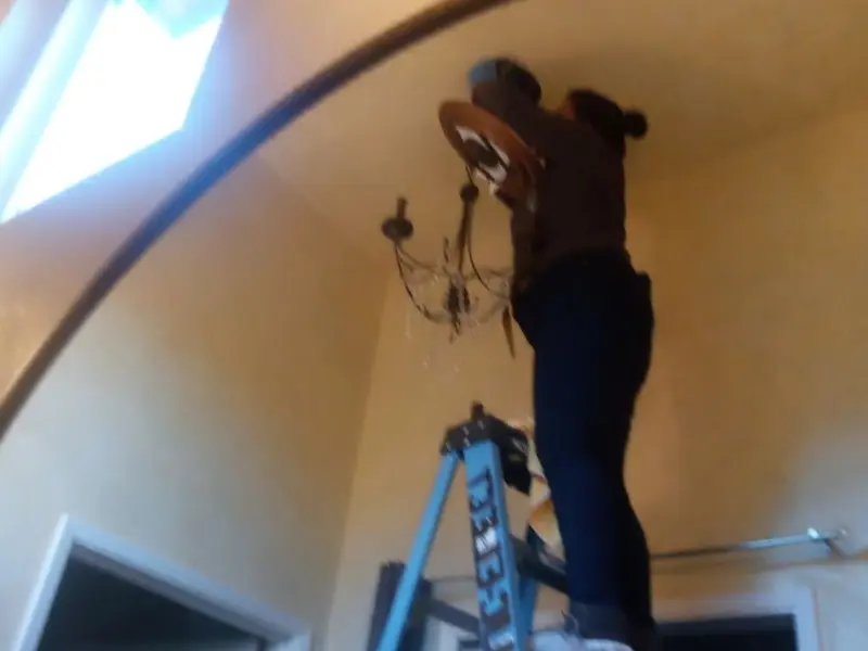 Electrician installing a chandelier in a Fulton residence